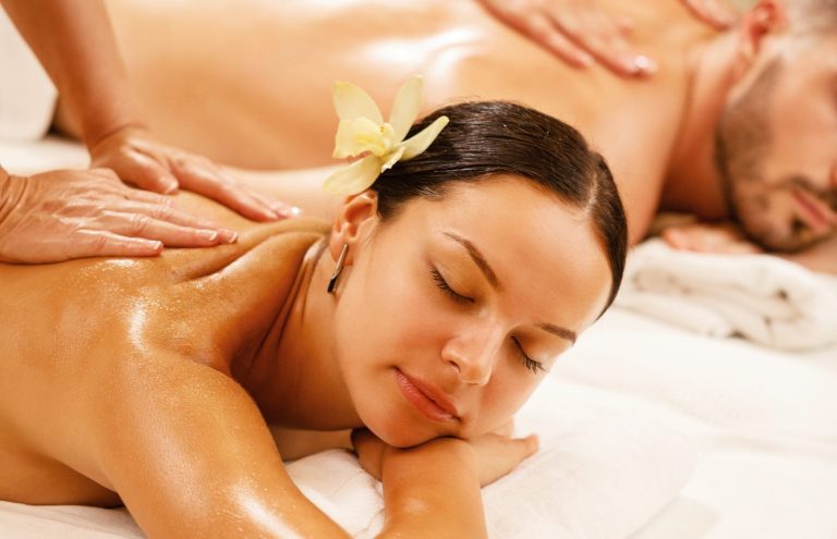 Massage duo relaxant aux huiles : une femme reçoit un massage du dos.