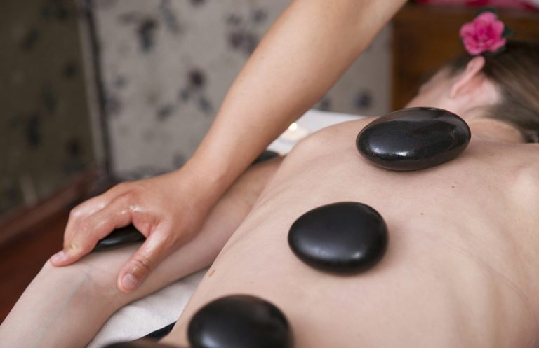 Une femme reçoit un massage du dos avec des pierres chaude.