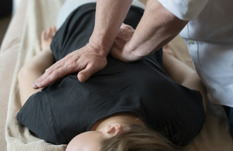 Une femme reçoit un massage du dos avec des pierres chaude.