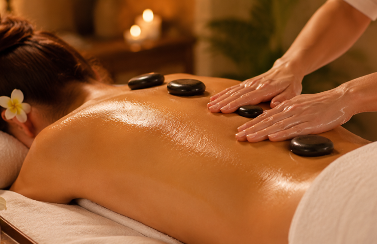 Une femme reçoit un massage du dos avec des pierres chaude.